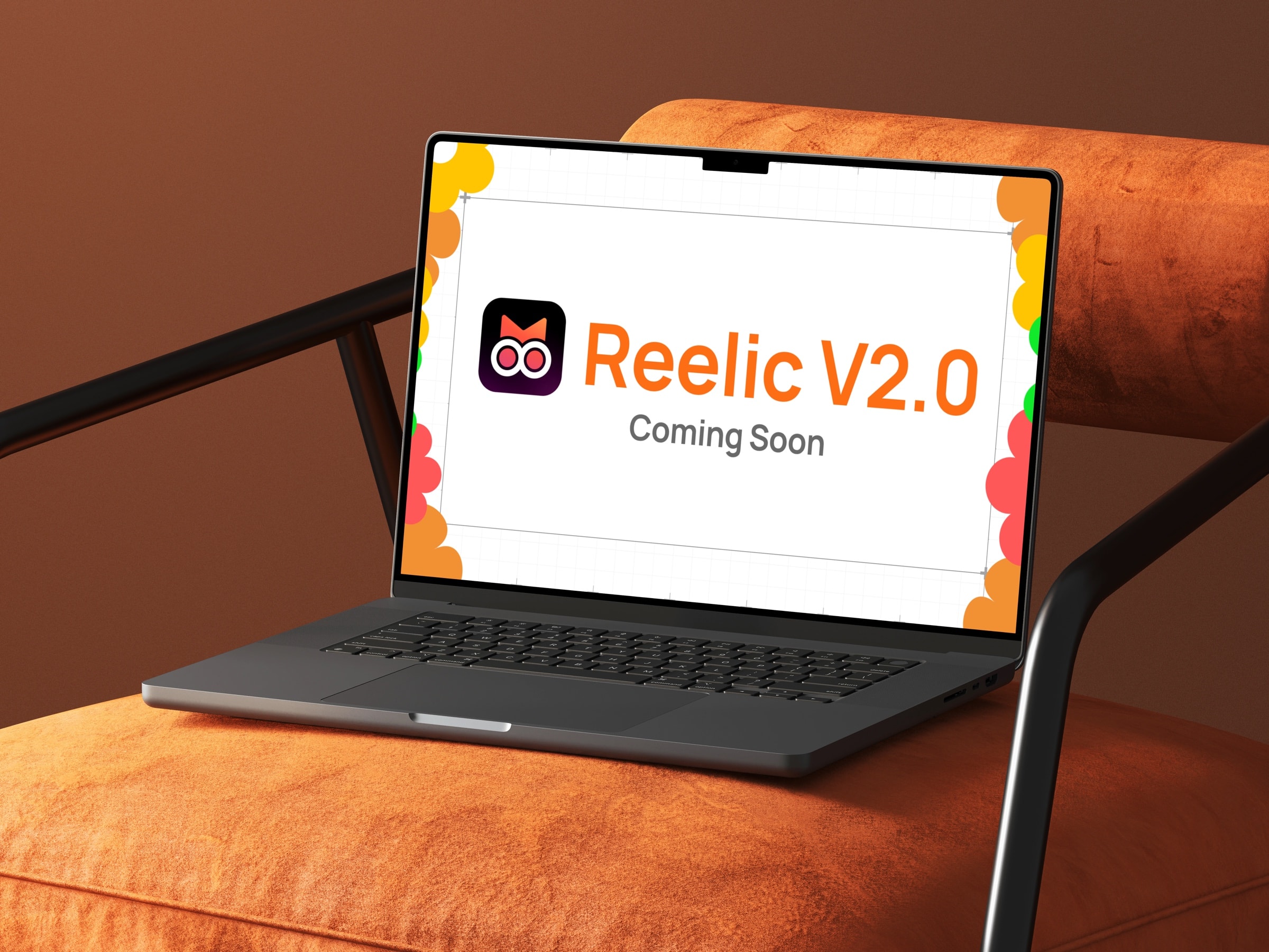 A laptop on a tan chair showing a Reelic V2.0 Coming Soon title card framed by the brand's flower motif